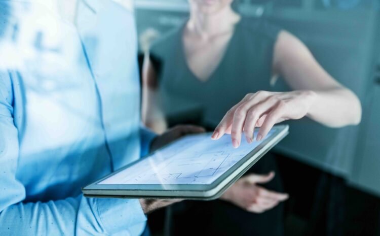 Midsection of young unrecognizable businesspeople with tablet in an office, working. Shot through glass.